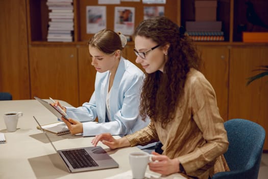 In a modern office, two talented women have a significant discussion and collaborate productively on important work