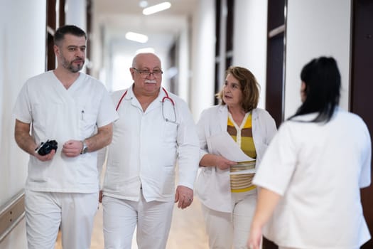 A group of healthcare professionals in white uniforms walking through a hospital hallway while reviewing patient documents and discussing treatment plans