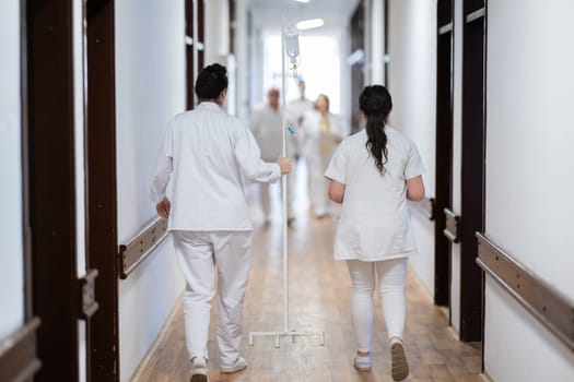 A group of healthcare professionals in white uniforms walking through a hospital hallway while reviewing patient documents and discussing treatment plans
