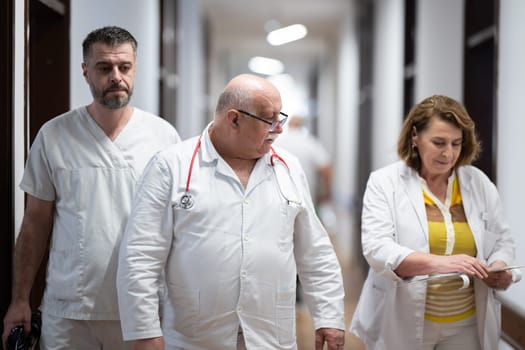A group of healthcare professionals in white uniforms walking through a hospital hallway while reviewing patient documents and discussing treatment plans