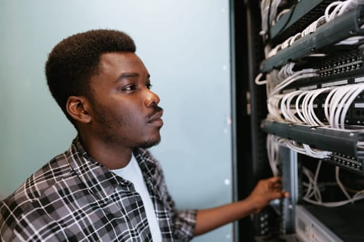A technician inspects and organizes network cables in a server room. The professional focuses on ensuring proper connections during the daytime, highlighting efficient network management.