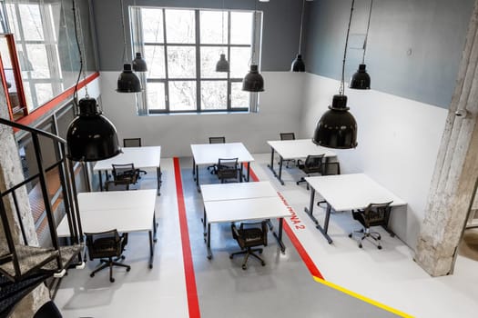 Bright, spacious workspace features several desks arranged for team collaboration. Large windows allow natural light to fill the area, enhancing productivity and creativity.
