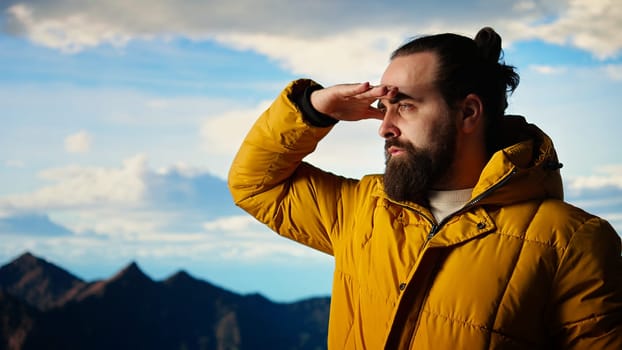 Male explorer standing at a scenic viewpoint appreciating the peaceful beauty of the mountains, successful climb. Trekker admires high altitude freedom and mental clarity. Camera A.