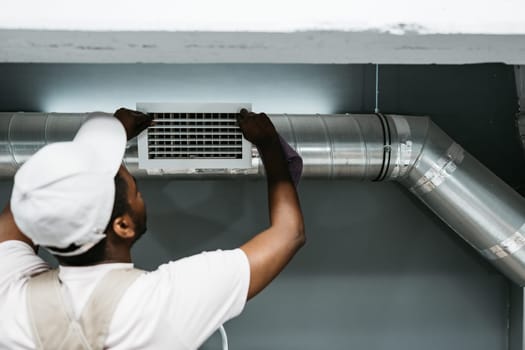 A skilled technician is installing an air duct in a residential setting, focusing on precise adjustments. The workspace is well-lit, highlighting the installation process.