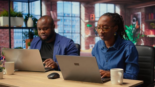 African American couple works from home collaborating on a freelance project in their modern loft, using a laptop to plan strategies, boost productivity and achieve business success. Camera A.