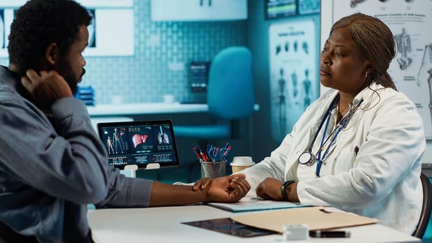 African american medic monitoring pulse and heartbeat with a smartwatch for a patient, looking at her wrist watch fitness tracker accessory during checkup. Heart rate measurement. Camera A.