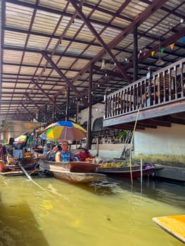 Bangkok, Thailand - November 12, 2024: Traditional floating market in boats of produce, market vendors sell Thai food, fruits and seafood from boats. Thailand culture and tropical bazaar.
