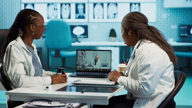 Physician calling the expert practitioner on video conference with a patient, creating a telehealth consultation for a second opinion. Medical staff using high tech equipment at clinic. Camera A.