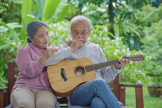 Asian senior couple elderly man playing guitar while his wife singing together outdoors at house, Activity family health care, Enjoying lifestyle during retirement life having fun of senior older