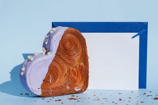 Empty paper note card template mock up Heart shaped blueberry flavor croissant on blue background with copy space. Puff pastry new trendy sweet dessert bakery. Creamy dough experiment