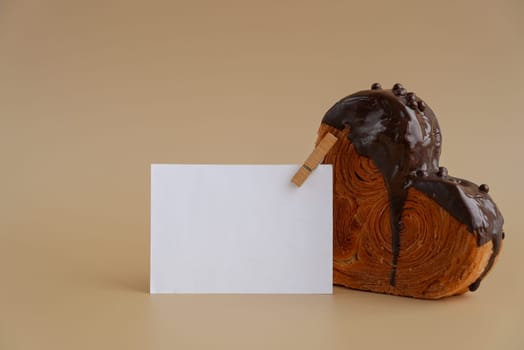 Empty paper note template sample mock up blank for wishes greeting holiday card Heartshaped pastry croissant treat topped with colorful frosting galore. Food experimentation viral dessert creative baking trend