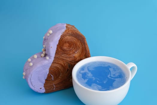 Blue drink Matcha beverage superfood Valentine's Day Birthday holiday present gift idea Delightful and vibrant heartshaped pastry croissant treat, beautifully topped with colorful frosting galore. Copy space. Food experimentation viral dessert creative baking trend