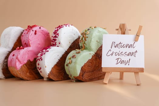 Holiday celebration NATIONAL CROISSANT DAY text Heart shaped different variety flavor croissants on beige background with copy space. Puff pastry new trendy sweet dessert bakery. Creamy dough experiment