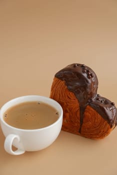 Coffee latte cappuccino drink beverage morning breakfast Heart shaped dark chocolate croissant on beige background with copy space. Puff pastry new trendy sweet dessert bakery. Creamy dough experiment