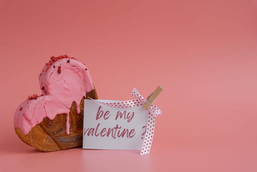 valentine's day BE MY VALENTINE saying caption on greeting card Delightful and vibrant heartshaped pastry croissant treat, beautifully topped with colorful frosting galore. Copy space. Food experimentation viral dessert creative baking trend