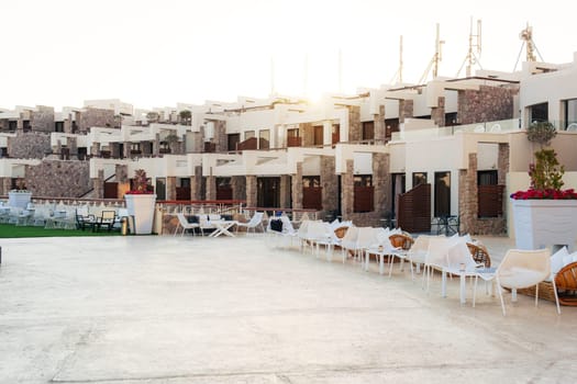 Luxurious resort complex with contemporary design showcases elegant outdoor seating and a beautifully landscaped area under a clear sky at sunset.