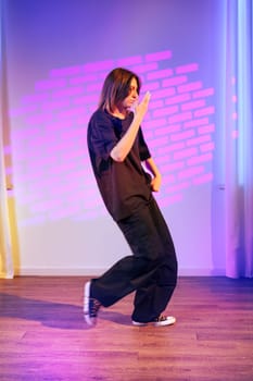 A dancer showcases skillful movements in a dynamic routine within a contemporary studio. The vibrant lighting adds flair to the energetic atmosphere.