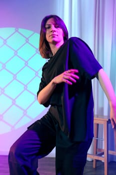 A dancer captivates the audience with expressive movements on stage while illuminated by colorful lights in a contemporary theater. The atmosphere evokes energy and creativity.