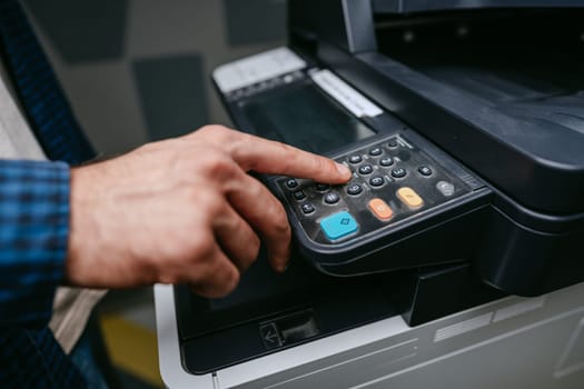 A person is engaging with a multifunction printer's control panel, pressing buttons in an office setting. The atmosphere reflects a typical workday, focused on completing tasks efficiently.