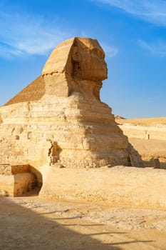 The Great Sphinx stands majestically at Giza, showcasing its massive stone body and detailed features. The bright midday sun highlights the ancient monument's grandeur against a clear sky.