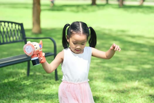 Cheerful little girl in pink dress enjoying outdoor playtime.