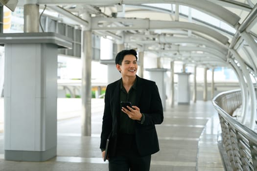 Smiling adult businessman with a phone in hand commuting to work.
