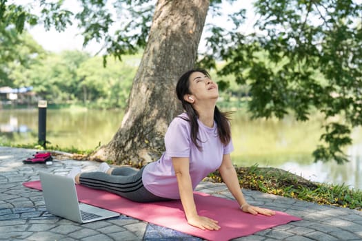A woman performs yoga poses on a mat by the lake, embracing wellness and mindfulness in a natural setting.
