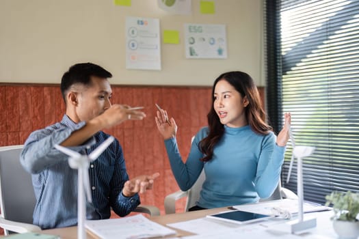 A man and woman discuss ESG initiatives in a modern office setting, highlighting sustainability and business collaboration.