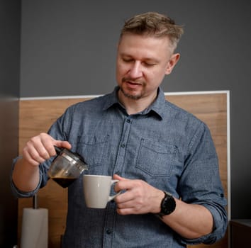 Handsome Man Pouring Himself Coffee At Home In The Kitchen