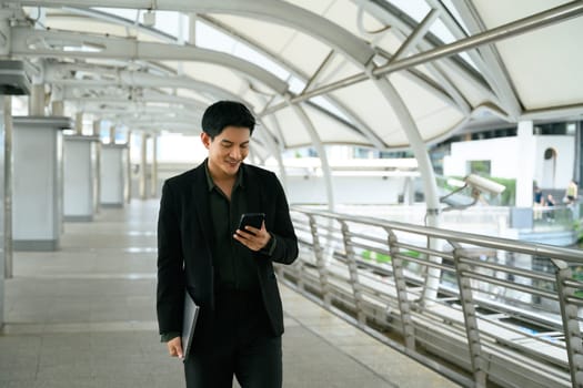 Smiling adult businessman with a phone in hand commuting to work.