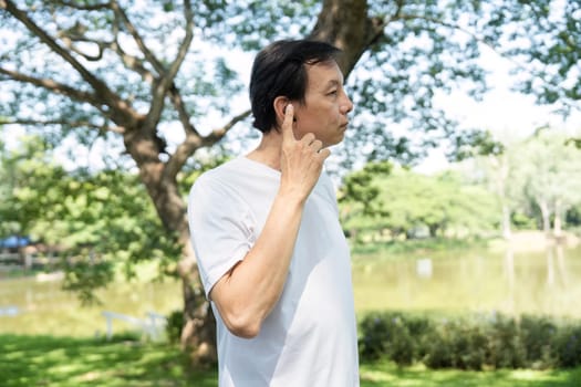 An older man engages in stretching exercises outdoors, promoting wellness and physical activity in a serene park setting.