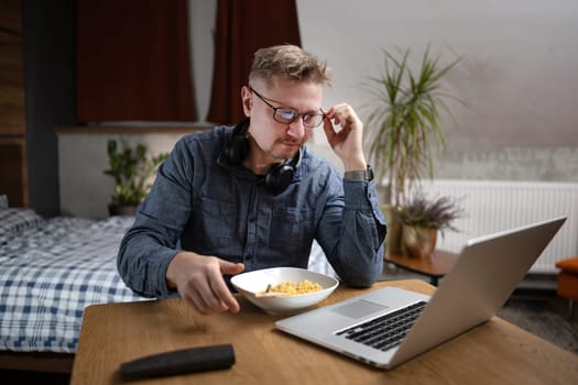 Man Eats Dinner While Working Remotely On Laptop At Home