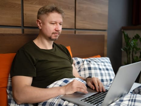 Man Watching News On Laptop In The Morning In Bed