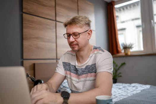 Man Working Remotely On Laptop At Home In Bedroom