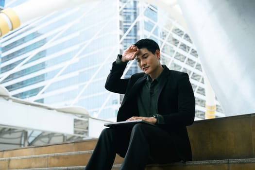 Male worker in businesswear displays signs of burnout or fatigue in an urban environment.