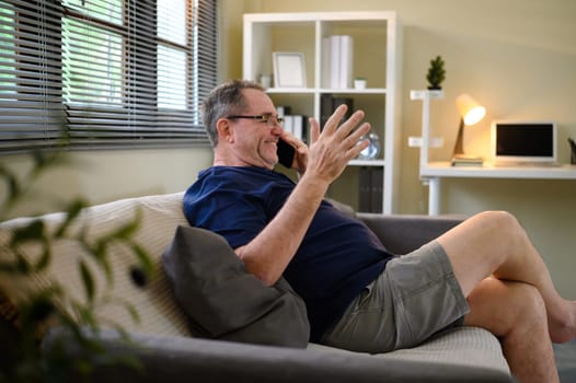 Happy senior man chatting on phone at home.