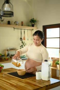 Pregnant woman pouring cereal for a healthy breakfast.