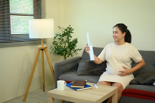 Pregnant woman lovingly admiring ultrasound while relaxing in warm and peaceful home.
