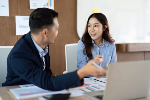 A businesswoman and businessman engaging in a lively discussion, showcasing teamwork and collaboration in a corporate environment.