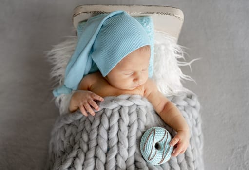 Newborn Baby Sleeping With Adorable Smile On A Little Bed In The Photo Studio