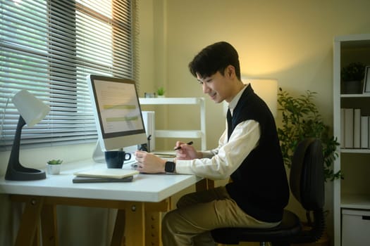 Young asian man working on monthly goals at home office.