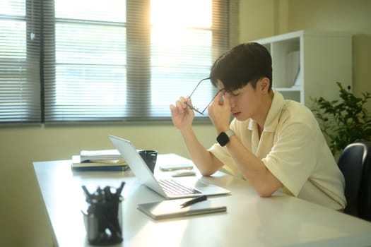 Tired businessman rubbing eyes after long screen time.