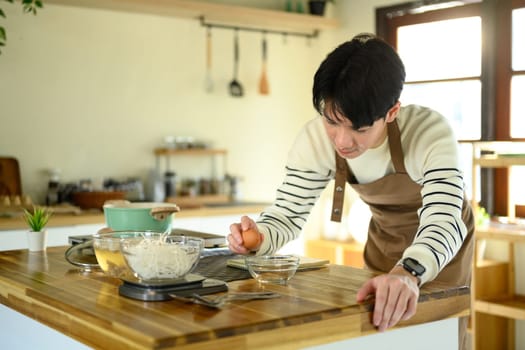 Happy Asian man cooking at home with fresh ingredients.