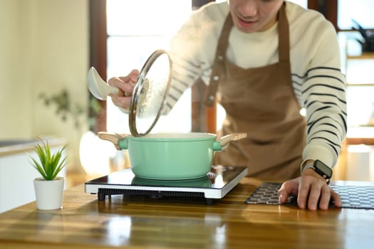 Happy Asian man cooking at home with fresh ingredients.