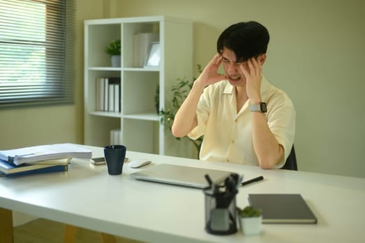 Stressed young man overwhelmed with work at home office.
