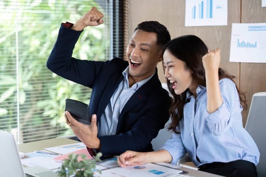 Two business professionals celebrating success while viewing positive results on a tablet, embodying teamwork and achievement.