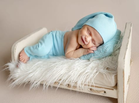 Newborn Baby Sleeping With Adorable Smile On A Little Bed In The Photo Studio
