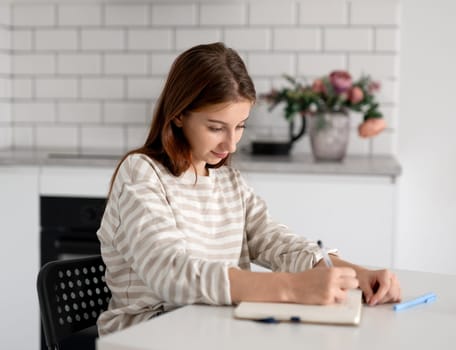 Happy Girl Doing Homework At Home At The Table