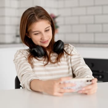 Girl Happily Playing On Smartphone At Home