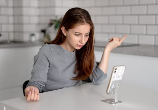 Unhappy Teen Girl Looking At Smartphone At Home
